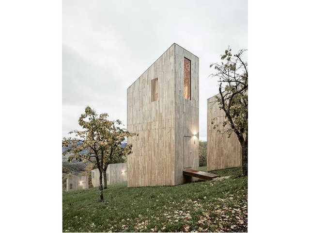 Ein kleiner Holzsteg führt direkt von der  Wiese zu den dreigeschossigen Hütten des Typs «Tree». 