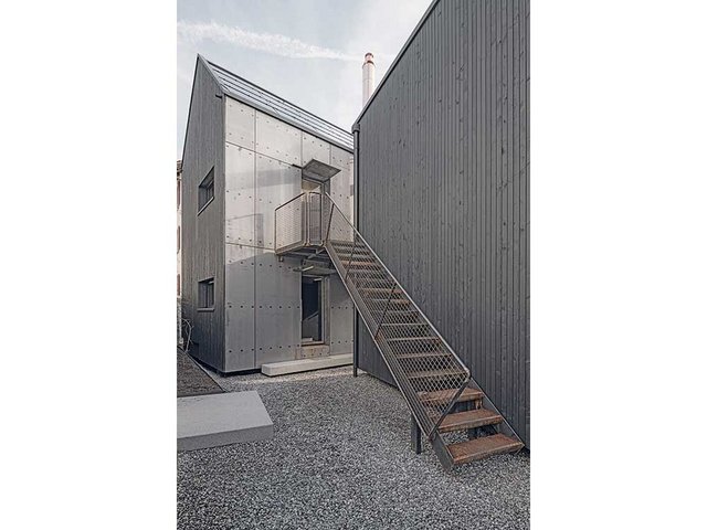 Ansicht West. Die Tiny-Häuser kommen ohne massives Fundament aus, die Holzrahmenbauten stehen auf Stahlträgern über dem gewachsenen Boden. Die Maisonettewohnungen sind über die Stahltreppe erschlossen. 