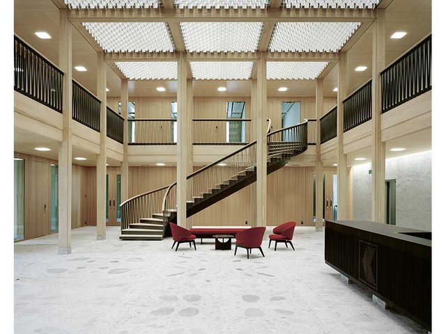 Eindrucksvolles Holztragwerk in der Eingangshalle: Die Unterzüge überspannen eine Länge von bis zu achteinhalb Metern. Insgesamt wurden für Tragwerk und Fassade 610 Kubikmeter Fichtenholz und 180 Kubikmeter Eschenholz verbaut. Für die Fertigung zeichnen die Küng Holzbau AG und die Holzbautechnik Burch AG verantwortlich. 