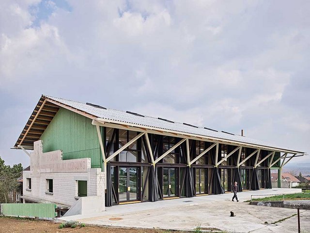 Bruchstückhaft erinnert die Aussenmauer an das frühere Weinlager. Neu ist der Holzrahmenbau auf dem massiven Bestandssockel. Das längliche Volumen unter dem flachen Satteldach teilt sich in sieben Einheiten: sechs Loftwohnungen und für alle Bewohner ein gedeckter Aussenraum mit Kochstelle.