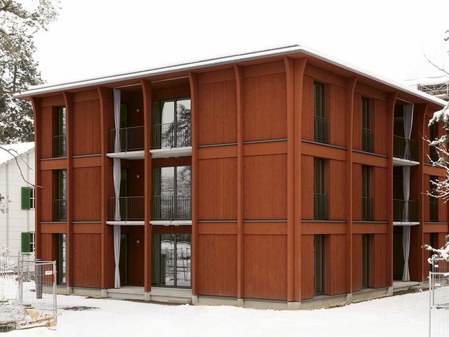Mehrfamilienhaus in Riehen: Der Holzmodulbau von Harry Gugger Studio / Erne AG Holzbau umfasst neun Mietwohnungen. Die Fassade ist so gestaltet, dass die Formate der Module ablesbar sind; spielerisch aufgebrochen wird die strenge Struktur durch Fassadenstützen, die am oberen Ende gebogen sind.